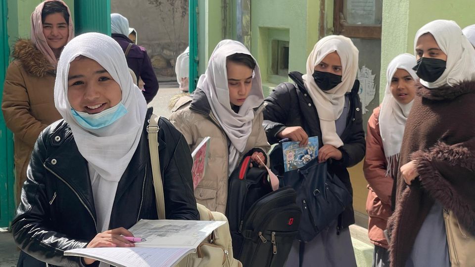Schoolgirls with headscarves Afghan schoolgirls with books stand in front of a building and talk.