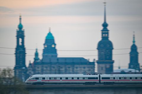 Sachsen, Dresden: Ein ICE der Deutschen Bahn fährt am Morgen vor der Altstadtkulisse über die Marienbrücke