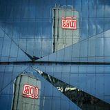 Das Logo der Bahn "DB" spiegelt sich am Morgen unter dem bewölkten Himmel in einem Bürogebäude am Berliner Hauptbahnhof