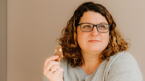 Abnehmen: Eine Frau hält ein Stück Schokolade in der Hand