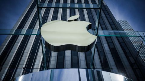 Das Logo von Apple hängt an einer gläsernen Fassade