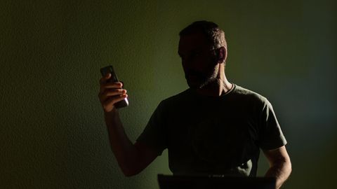 Silhouette eines Mannes, der auf sein Mobiltelefon schaut