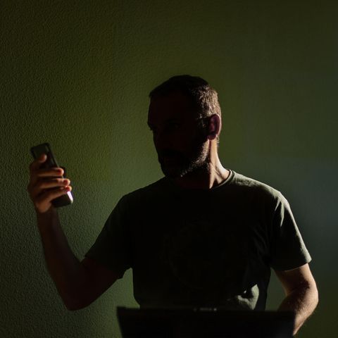 Silhouette eines Mannes, der auf sein Mobiltelefon schaut
