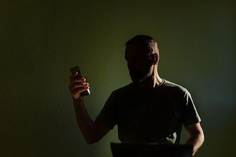 Silhouette eines Mannes, der auf sein Mobiltelefon schaut