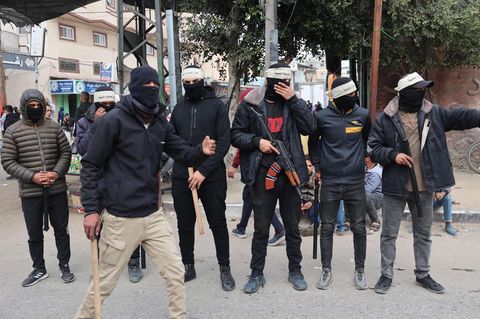 Die Ordnungsmacht der Clans: Mit Stöcken und einer Kalaschnikow bewaffnete junge Männer patrouillieren durch die Straßen von Rafah. Sie sollen verhindern, dass gestohlene Hilfsgüter zu Wucherpreisen auf dem lokalen Schwarzmarkt verkauft werden.