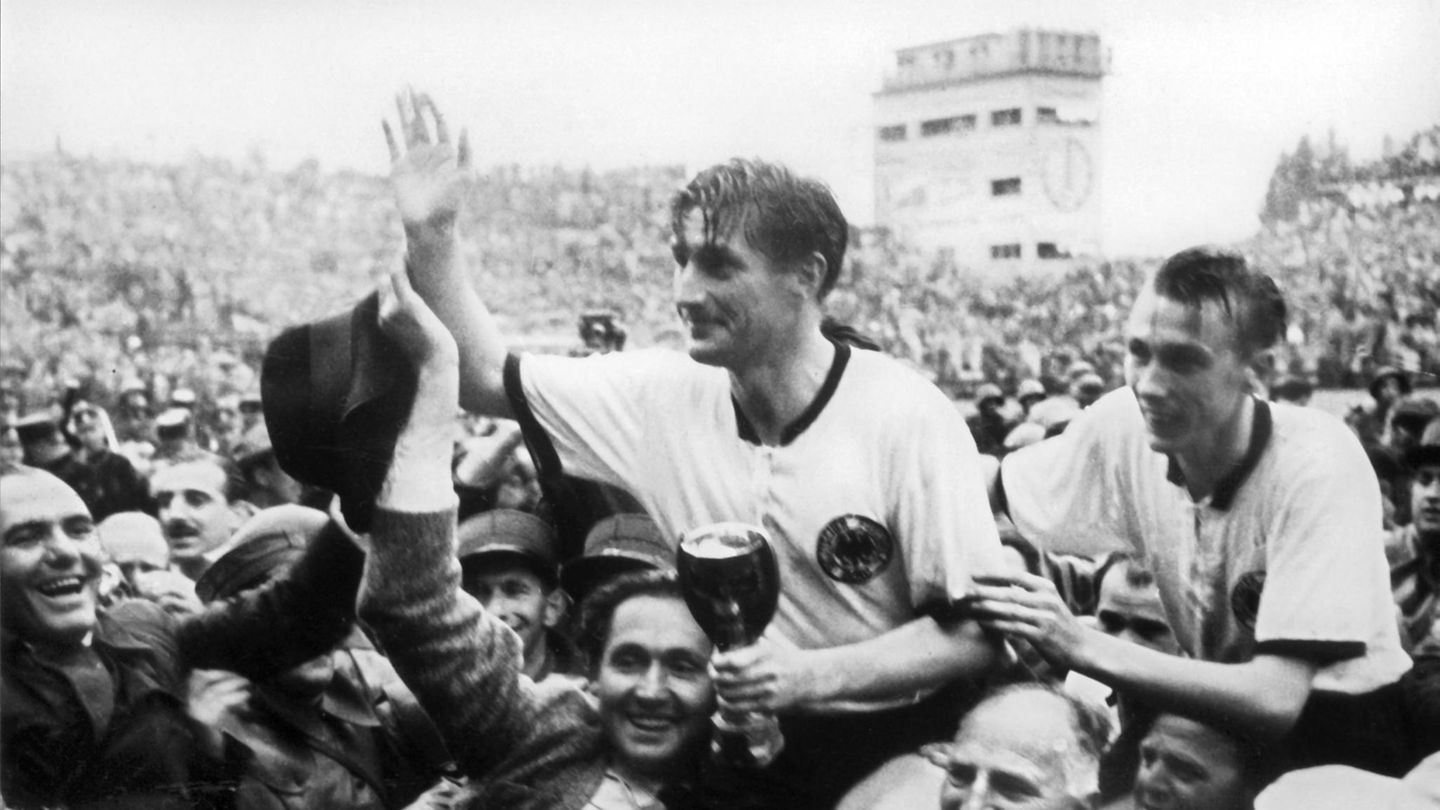 Die Adidas-Schuhe sollen ihren Anteil am "Wunder von Bern", dem WM-Sieg von 1954, gehabt haben. Die Trikots der Mannschaft um Kapitän Fritz Walter (M.) dagegen  – hier mit Teamgefährte Horst Eckel (r.) – stammten nicht von Adidas, sondern von der Marke "Leuzela", hergestellt von der Pfullinger Firma G. & A. Leuze. Später wurde der Hersteller von Erima aufgekauft.