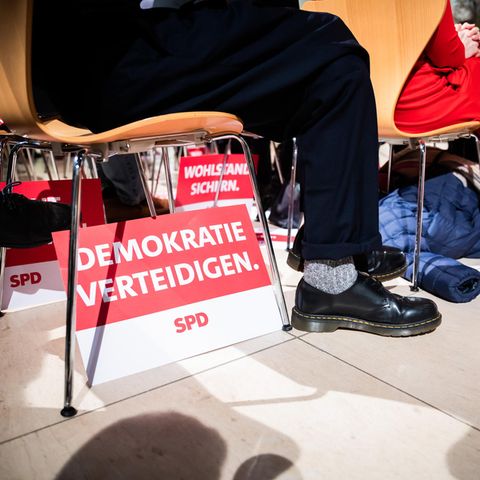 Unter einem Stuhl steht ein SPD-Schild mit der Aufschrift "Demokratie verteidigen".