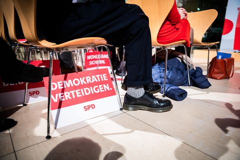 Unter einem Stuhl steht ein SPD-Schild mit der Aufschrift "Demokratie verteidigen".