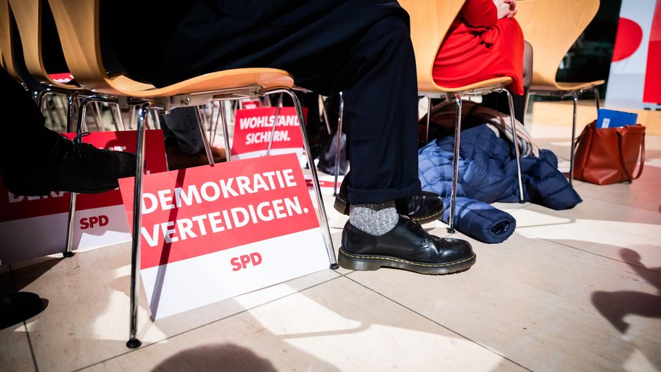 Unter einem Stuhl steht ein SPD-Schild mit der Aufschrift "Demokratie verteidigen".