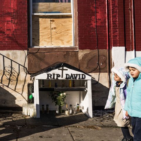 Alltag in Kensington, zwei kleine Mädchen in Winterjacken laufen an einem Mahnmahl für einen Drogentoten vorbei