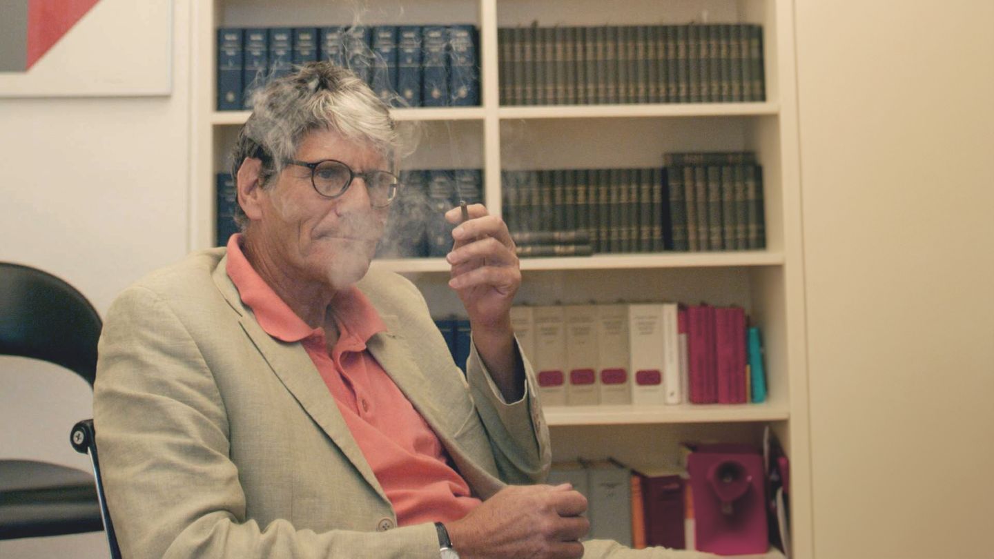 Rupert von Plottnitz sitzt in einem Stuhl und raucht eine Zigarette.