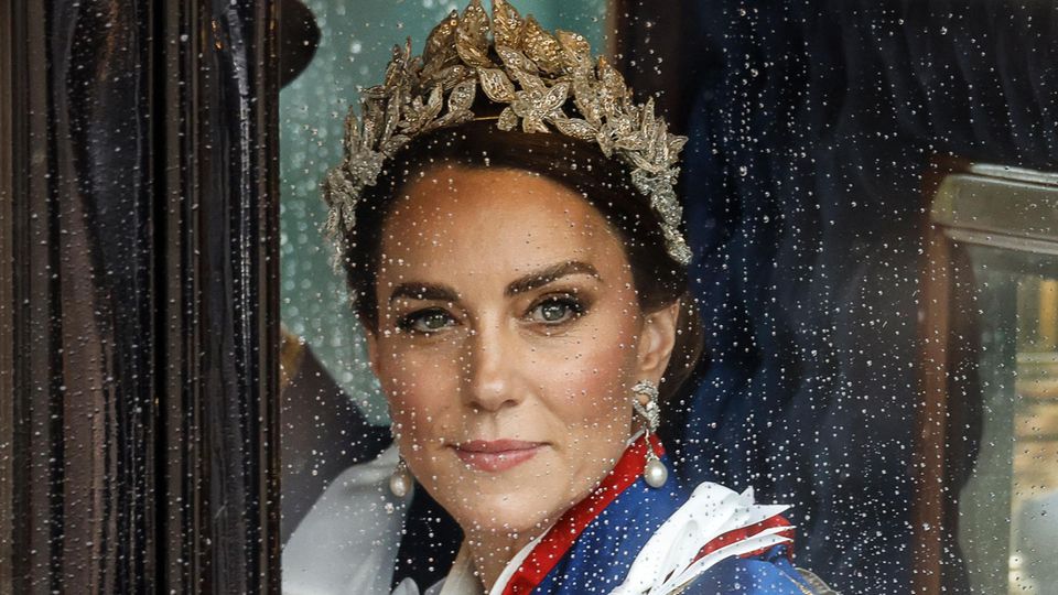 Kate nach der Krönungszeremonie in einer Kutsche, am Fenster fallen Regentropfen