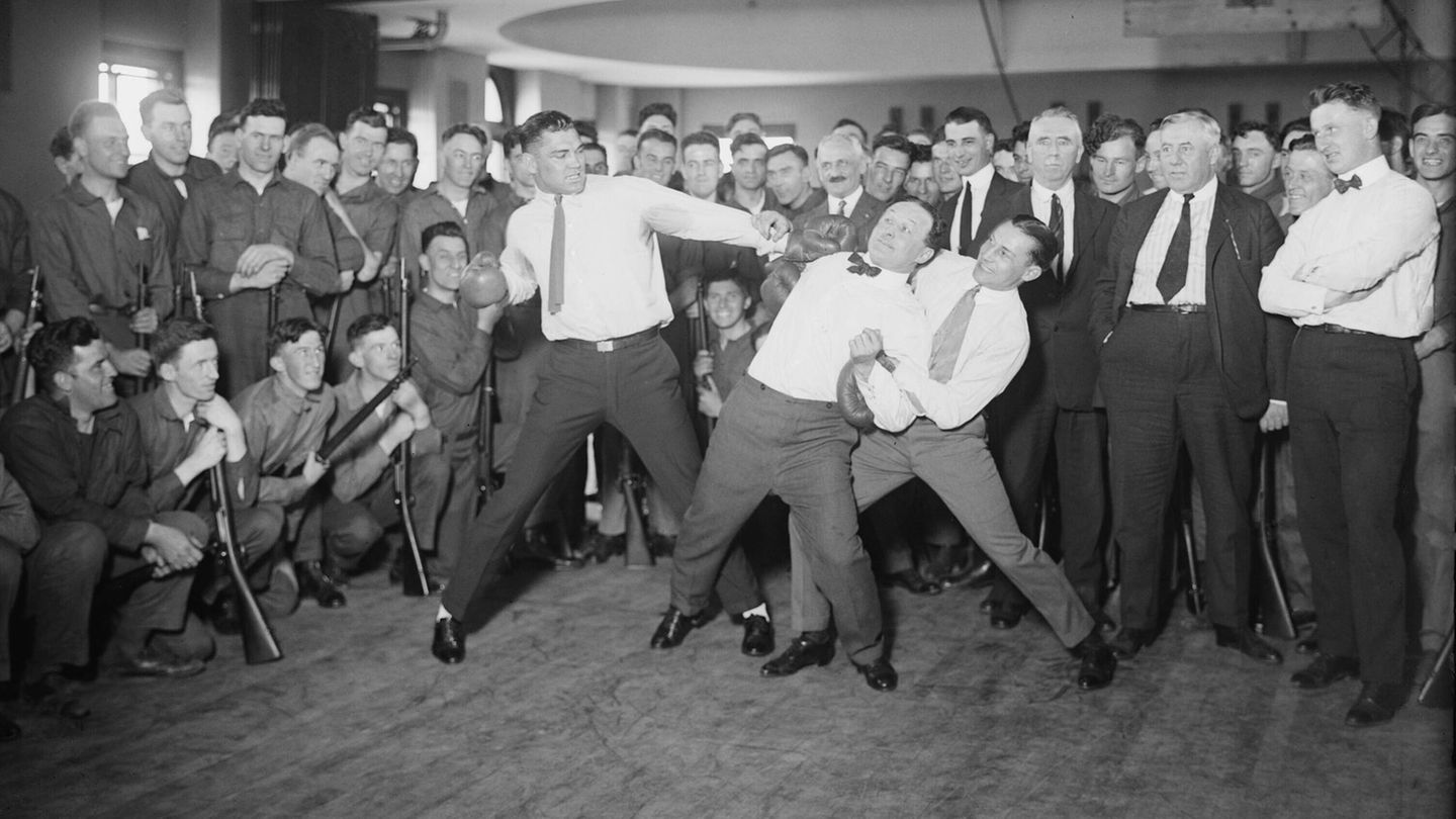 Ein Boxer hält Houdini fest, ein anderer holt aus um ihn zu schlagen