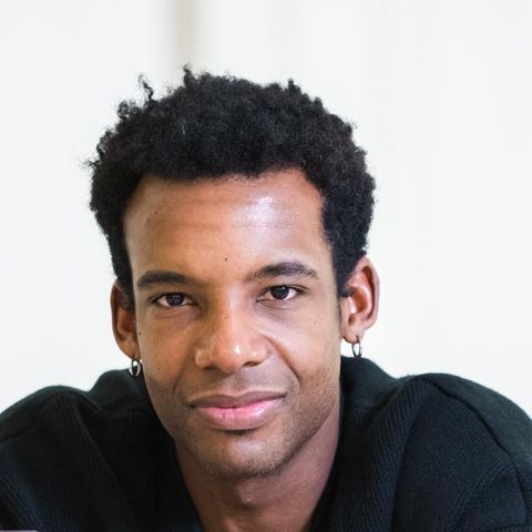 Osiel Gouneo schaut in die Kamera, er trägt ein dunkles Hemd und einen schwarzen, kurzen Afro