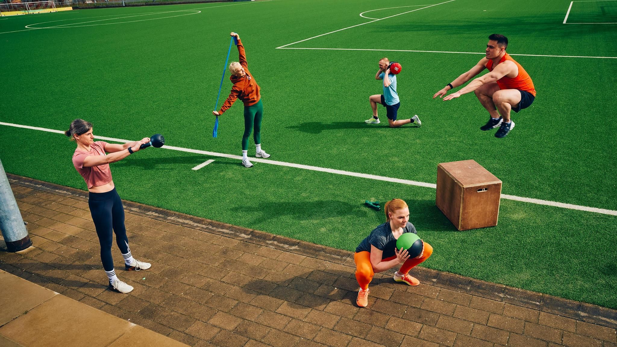 Mehrere Personen bei unterschiedlichen Übungen auf einer Sportanlage
