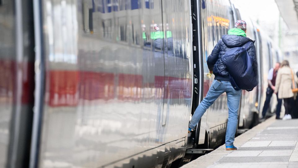 Ein Bahnreisender steht mit einem Fuß im ICE und schaut den Bahnsteig herunter