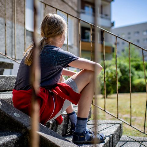 Kinderarmut: Ein Kind sitzt vor einem Plattenbau in Leipzig-Gruenau