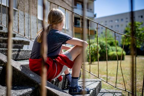 Kinderarmut: Ein Kind sitzt vor einem Plattenbau in Leipzig-Gruenau