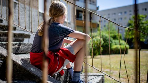 Kinderarmut: Ein Kind sitzt vor einem Plattenbau in Leipzig-Gruenau