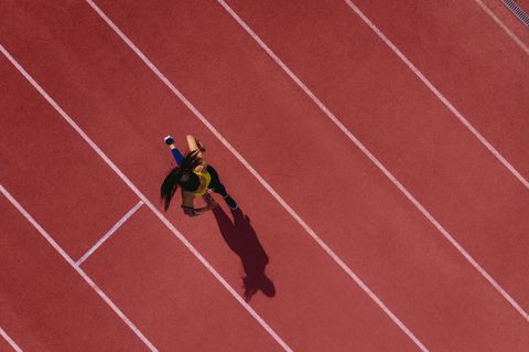 Läuferin hört Musik und läuft auf einer Sportbahn