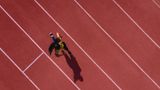 Läuferin hört Musik und läuft auf einer Sportbahn