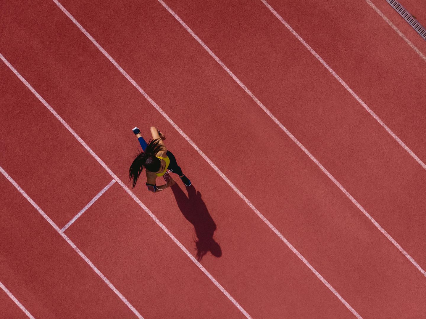 Läuferin hört Musik und läuft auf einer Sportbahn