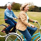 Ein älteres Paar fährt mit Fahrräddern einen Hügel hinunter.