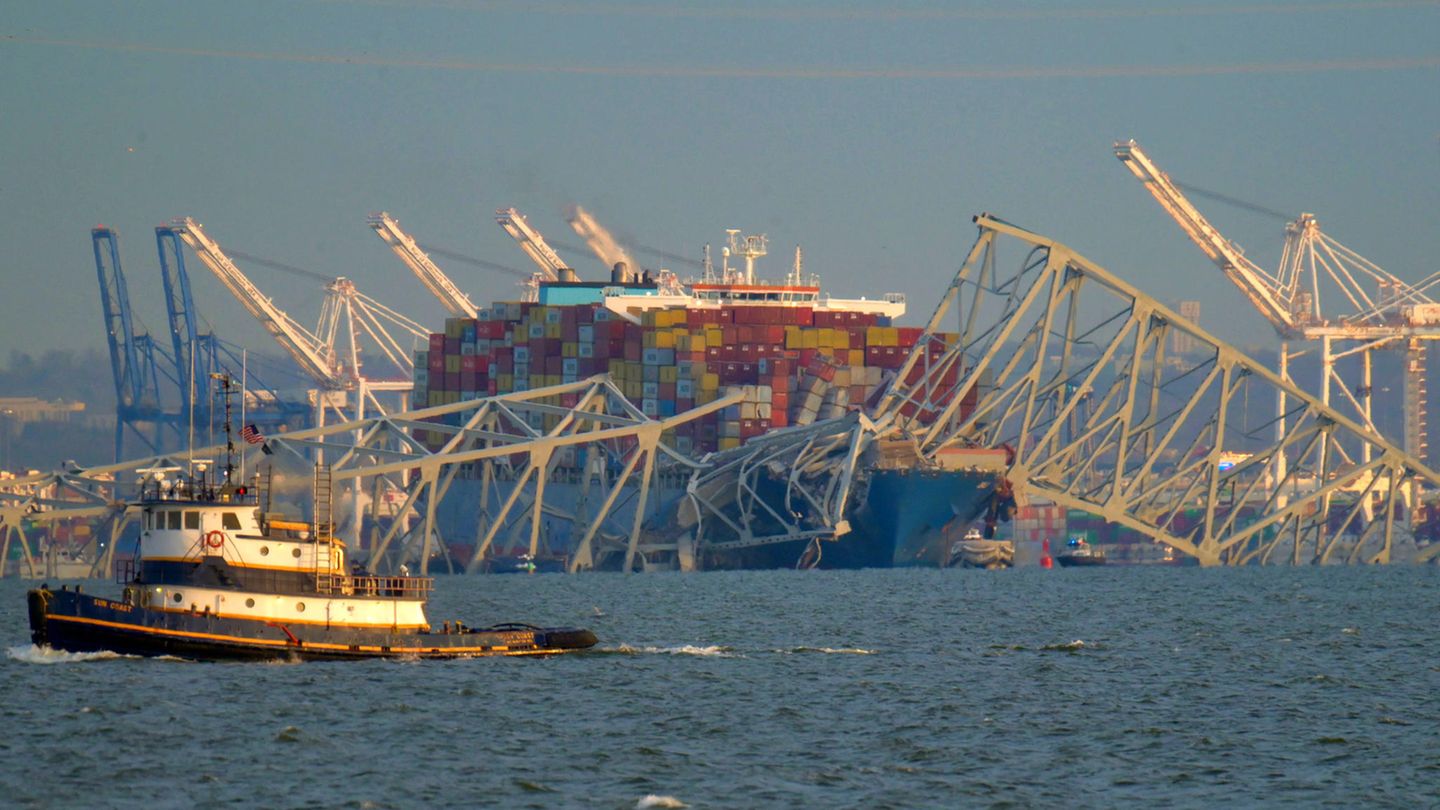 Baltimore : Das Containerschiff hatte kurz vor der Kollision im Hafen von Baltimore (im Hintergrund) abgelegt. Teile der stählernen Brücke sind auf den Bug des rund 300 Meter langen Schiffes gestürzt. Die Crew des Containerschiffs hat nach Angaben des örtlichen Gouverneurs kurz vor dem Zusammenstoß mit der Brücke einen Notruf abgesetzt. So seien Menschenleben gerettet worden, da die Behörden einen Teil des Straßenverkehrs über die Brücke stoppten, sagte Wes Moore vor Reportern. "Diese Leute sind Helden. Sie haben letzte Nacht Leben gerettet." Das Containerschiff hatte kurz vor der Kollision im Hafen von Baltimore (im Hintergrund) abgelegt. Teile der stählernen Brücke sind auf den Bug des rund 300 Meter langen Schiffes gestürzt. Die Crew des Containerschiffs hat nach Angaben des örtlichen Gouverneurs kurz vor dem Zusammenstoß mit der Brücke einen Notruf abgesetzt. So seien Menschenleben gerettet worden, da die Behörden einen Teil des Straßenverkehrs über die Brücke stoppten, sagte Wes Moore vor Reportern. "Diese Leute sind Helden. Sie haben letzte Nacht Leben gerettet."