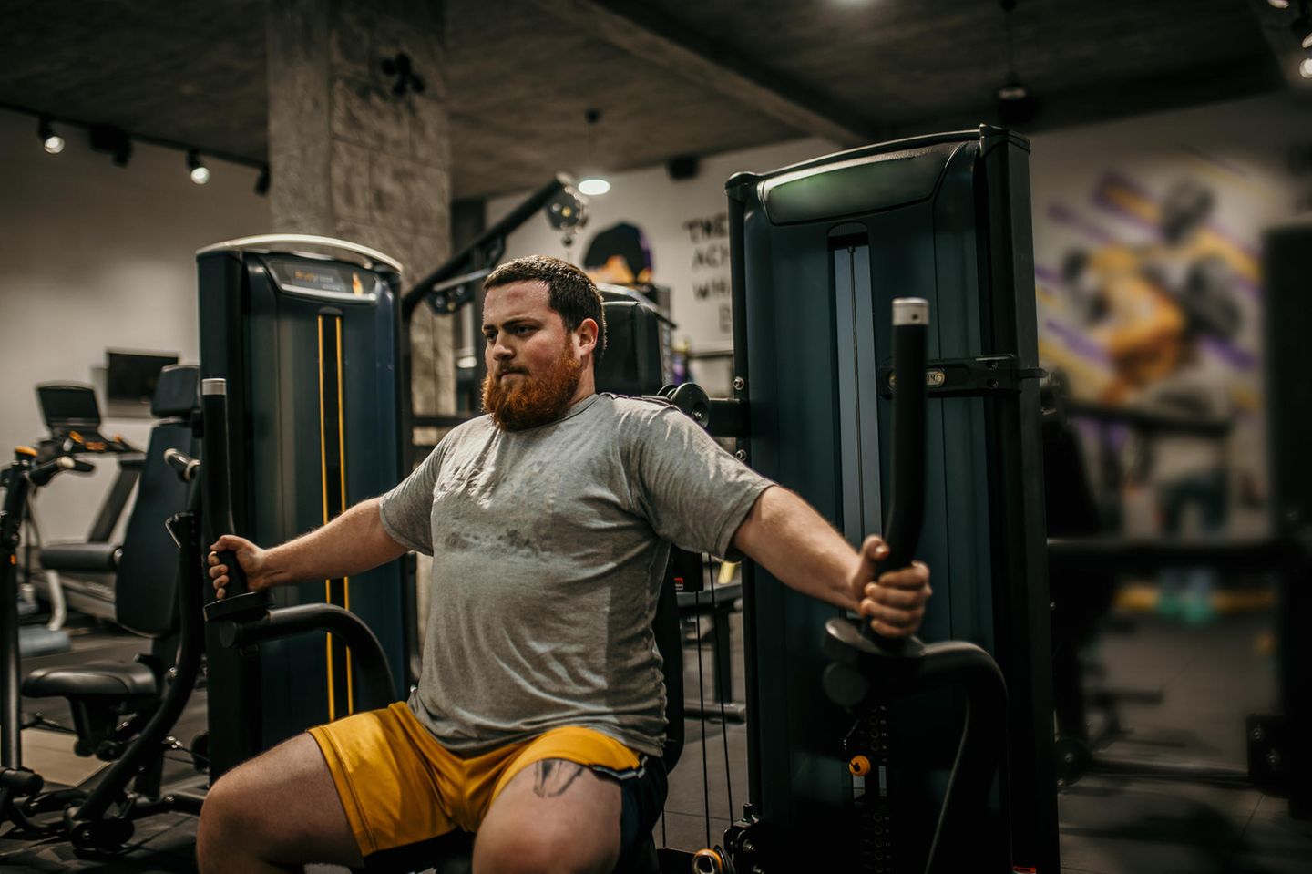 Ein Mann an einem Sportgerät im Fitnessstudio.