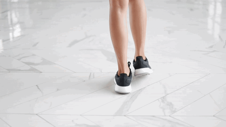 Fitness Eine Frau läuft in Sportschuhen eine grade Strecke entlang