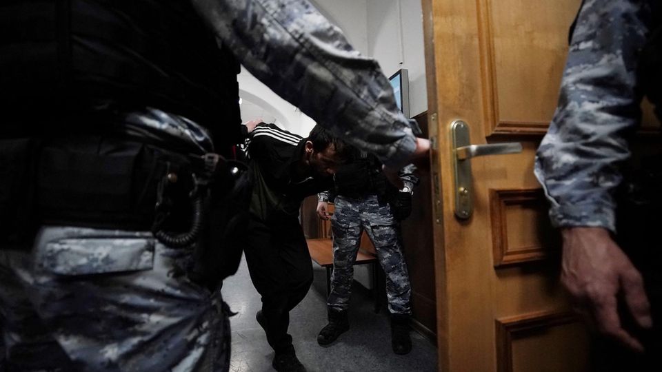 Ein Mann wird von russischen Strafverfolgungsbeamten eskortiert.