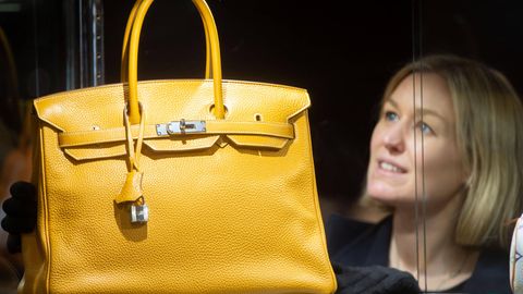 Eine Hermès-Mitarbeiterin präsentiert eine gelbe Handtasche des Modells Birkin
