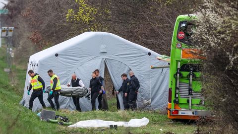 Bestatter tragen ein Todesopfer des verunglückten Busses von der Unfallstelle auf der A9 bei Leipzig