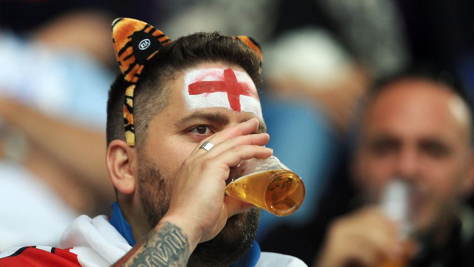 Ein England-Fan trinkt im Stadion ein Bier