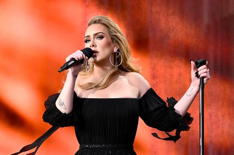 Adele sing auf der Bühne mit knallrotem Hintergrund