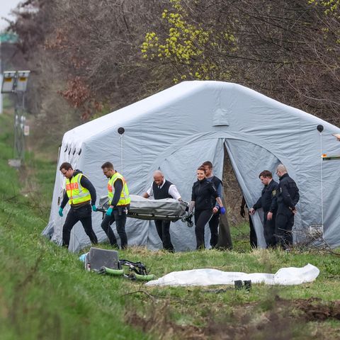An der A9 steht ein grüner Reisebus nach einem Busunglück zerstört an der Böschung