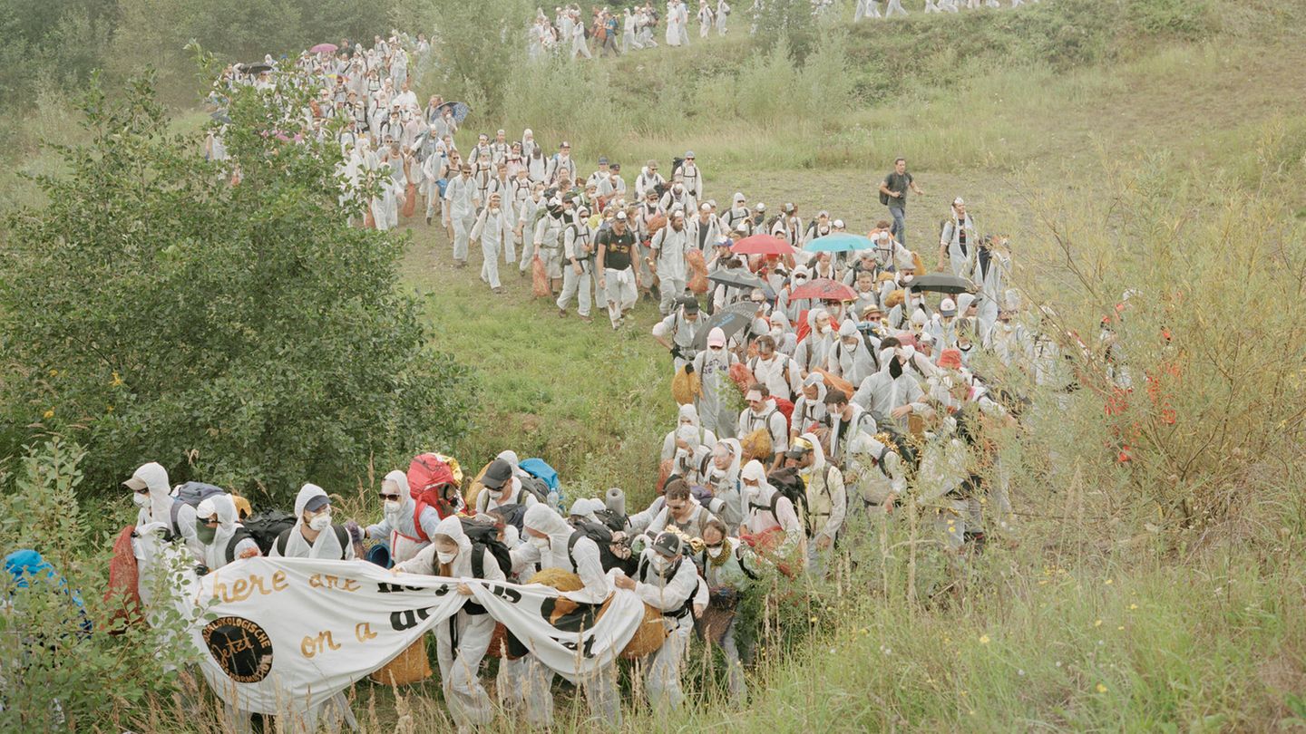 Demonstriernde marschieren durch eine Wiese