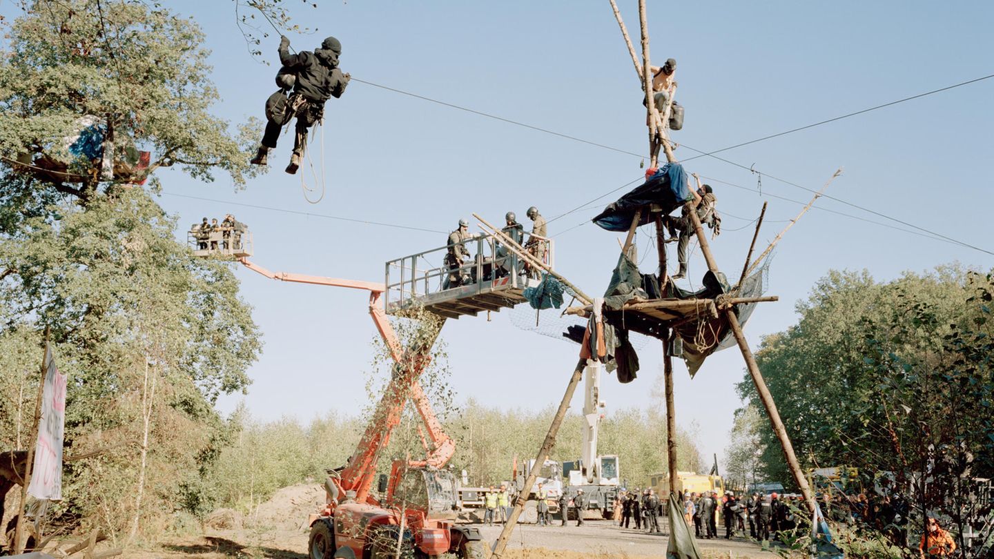 Aktivisten haben sich in luftiger Höhe auf einem Podest verschanzt und warten darauf von der Polizei herunter geholt zu werden.