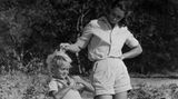 Jane Goodall in kurzer Hose fährt ihrem Sohn durch die Haare