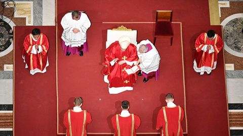 Papst Franziskus ist an Karfreitag von oben fotografiert, er sitzt auf einem Stuhl der auf einem roten Teppich steht.