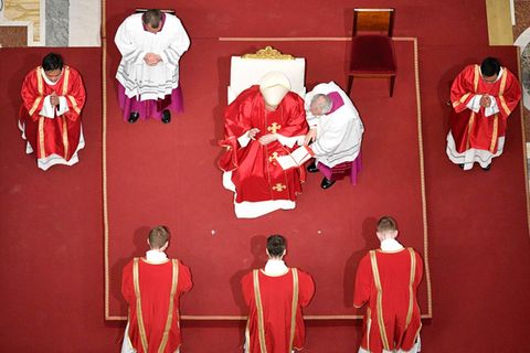 Papst Franziskus ist an Karfreitag von oben fotografiert, er sitzt auf einem Stuhl der auf einem roten Teppich steht.