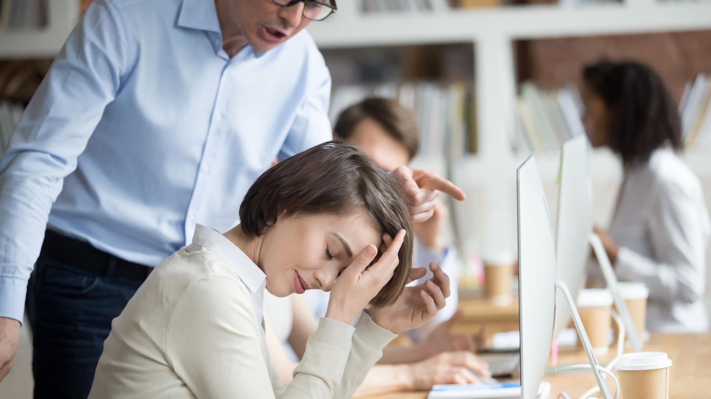 Karriere: Ein Mann ermahnt eine Frau, die am Schreibtisch sitzt