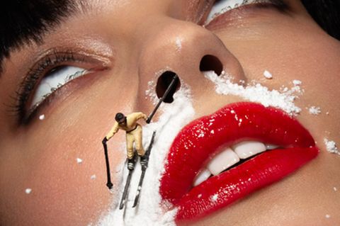 Nahaufnahme Frauengesicht. Miniatur-Skifahrer fährt runter auf der "Schneespur", die von Nasenlöchern über die Oberlippe läuft.