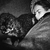 Janne und Pudel Happy liegen aneinander gekuschelt schlafend unter einer Decke.