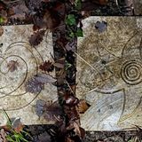 Verzierte Bodenplatten zwischen Laub