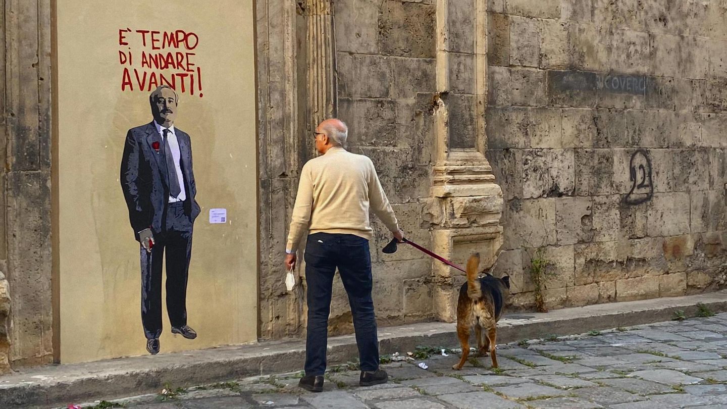 Ein Graffiti von Falcone. Davor steht ein Mann mit Hund