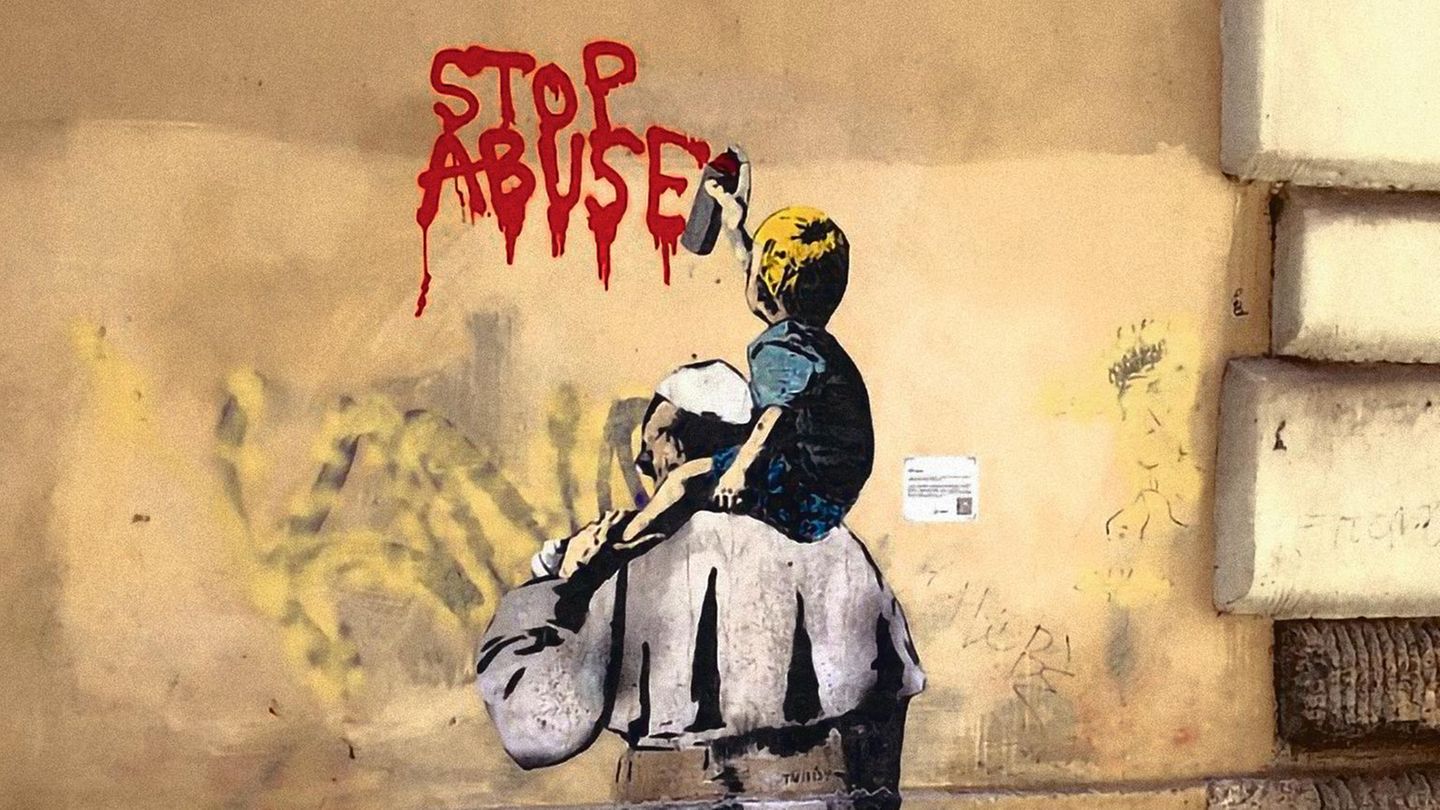 Ein Graffiti von dem Pabst mit einem Kind auf den Schultern. Das Kind sprüht in englisch Stoppt den Missbrauch auf die Wand