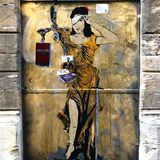Ein Graffiti von Justitia Sie hebt eine Seite der Augenbinde