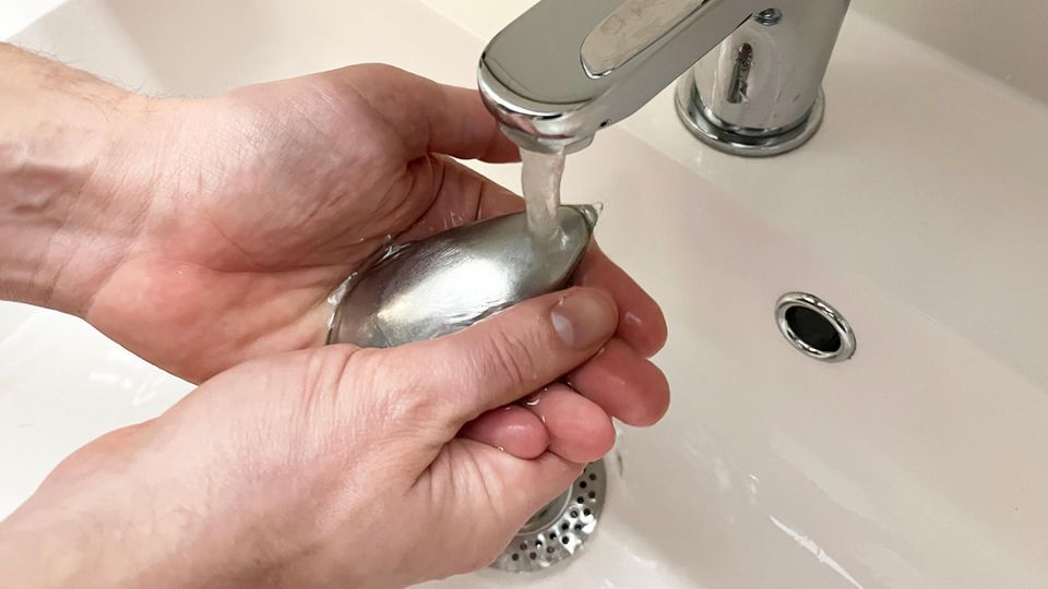 Ein Mann wäscht sich die Hände mit einer Edelstahlseife