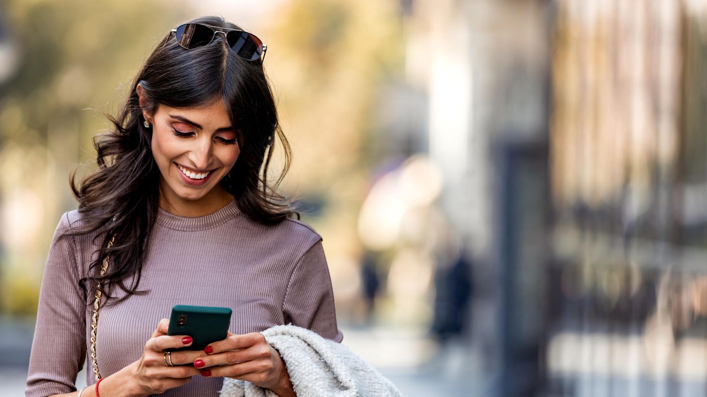 Lachende Frau mit Handy in der Hand freut sich über 200 Gigabyte Datenvolumen extra.